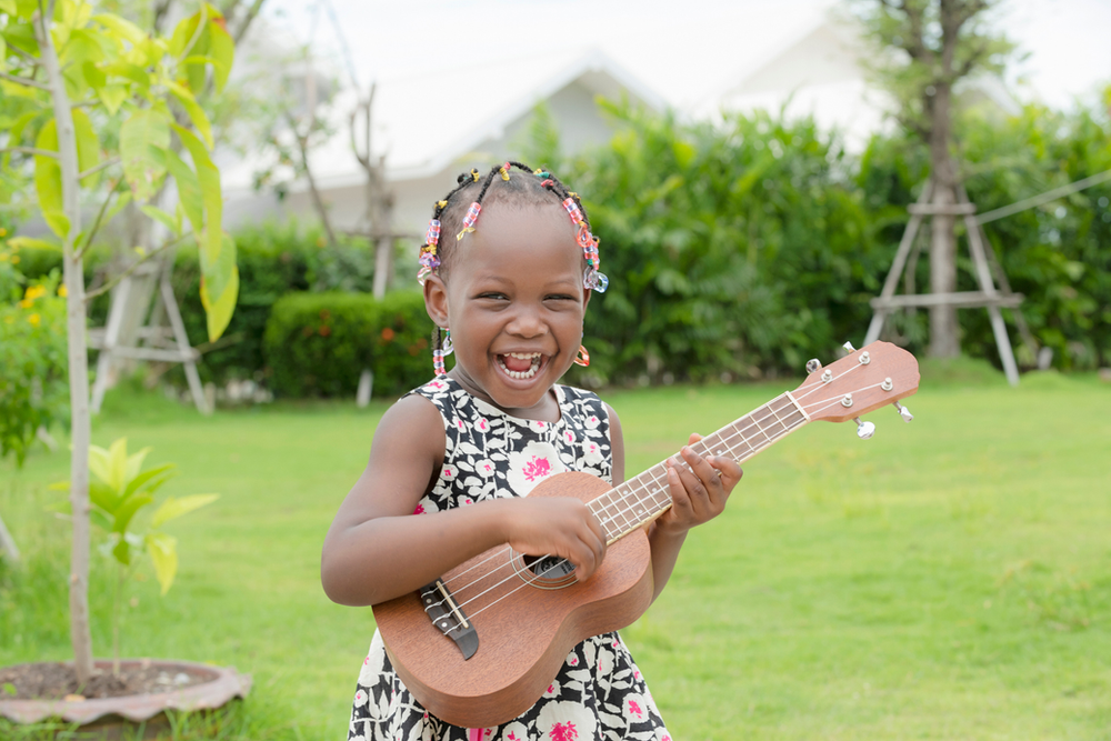 Young girl happy to be playing the ukulele